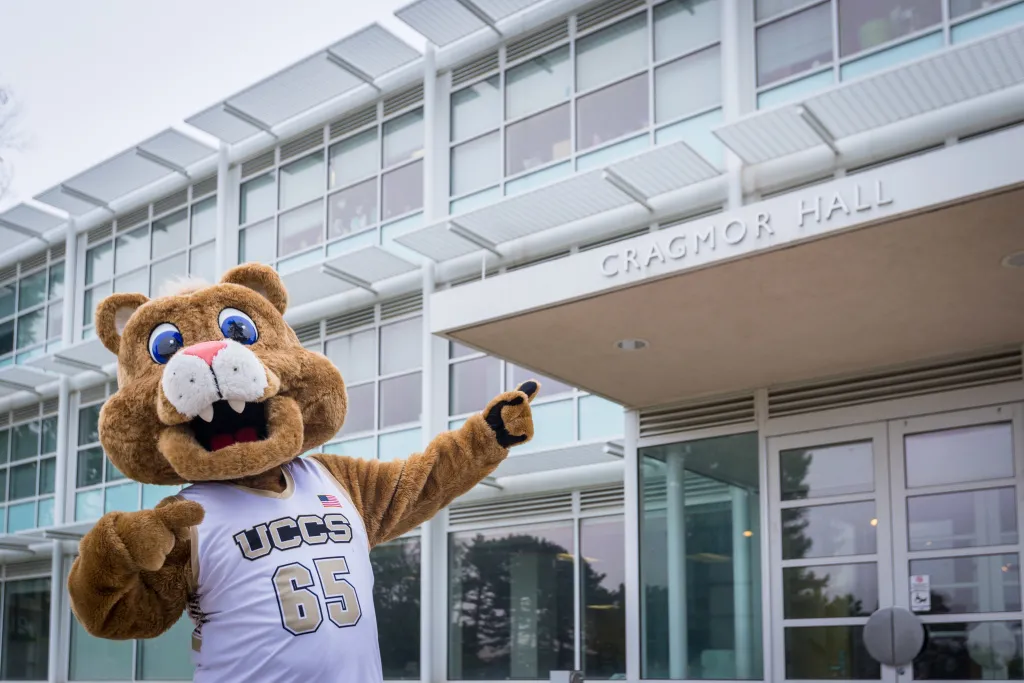 Clyde, the UCCS mascot, pointing at the entrance to Cragmor